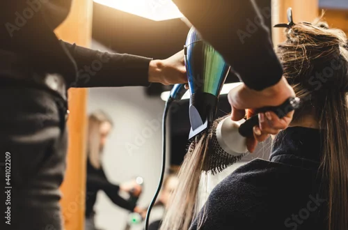 Obraz Master woman hairdresser dries the girl's hair with a hairdryer after washing in a beauty salon.