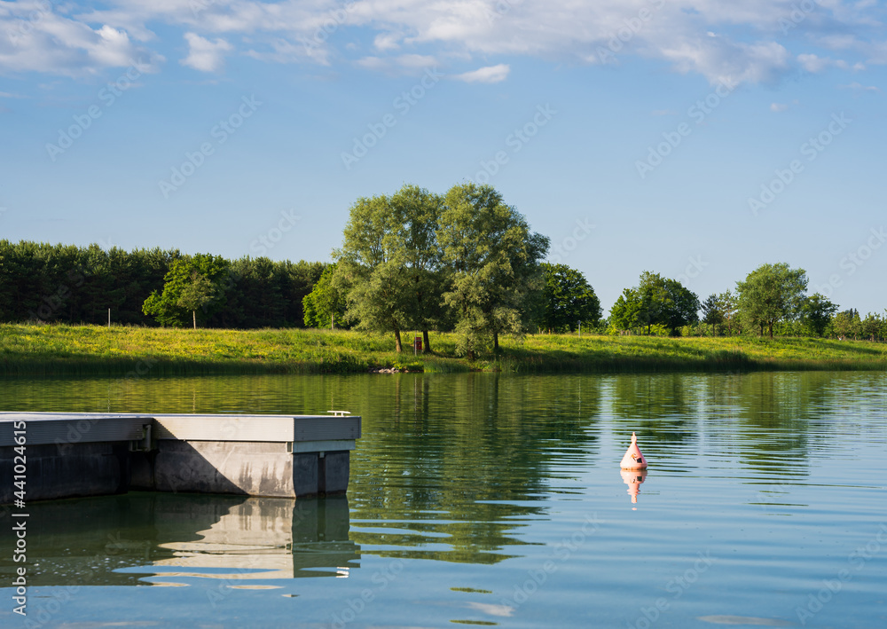 Fototapeta premium Colorful Lake with a Tree in the middle and a jetty on the left 
