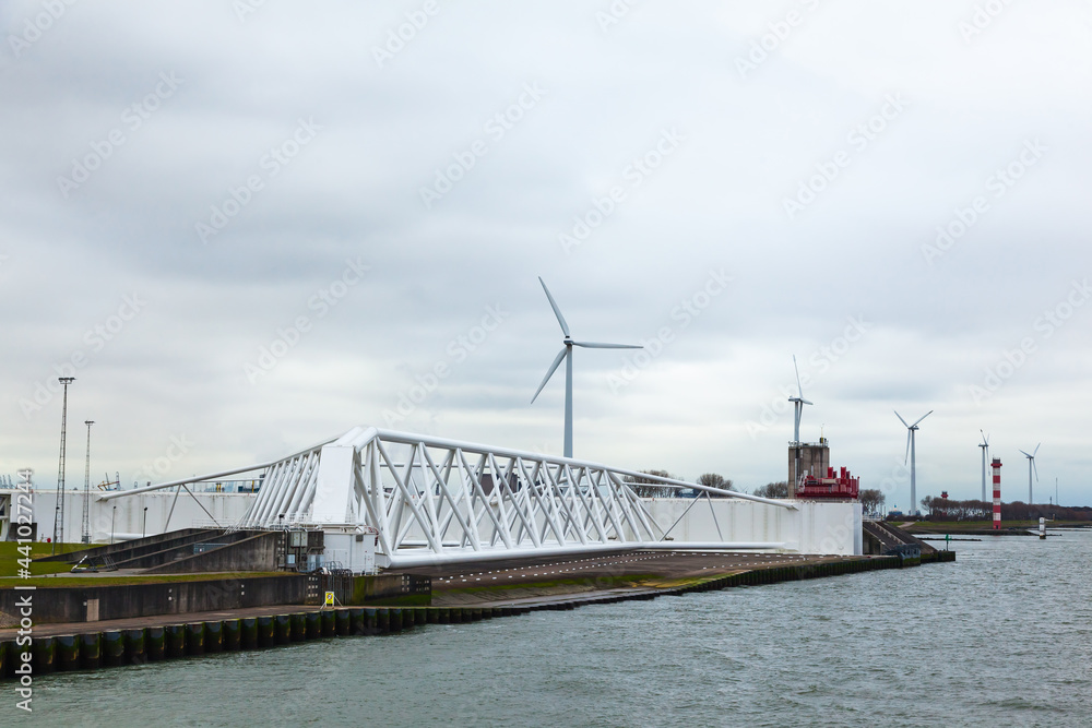 A canal in the suburbs of Rotterdam with a sliding bridge and wind generators. A canal in the suburbs of Rotterdam with a sliding bridge and wind generators.
