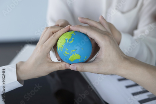 Global business, technology and people concept.Business people holding globe in meeting