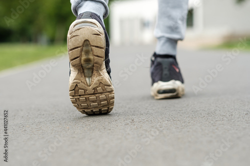close up of old dirty shoes trainers, walking in a park.