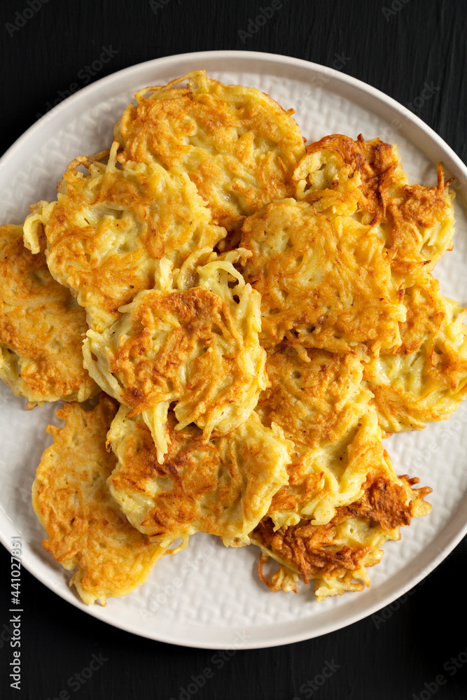Homemade Potato Pancakes Latkes with Apple Sauce and Sour Cream on a black wooden surface, top view. Flat lay, overhead, from above. Homemade Potato Pancakes Latkes with Apple Sauce and Sour Cream on a black wooden surface, top view. Flat lay, overhead, from above.