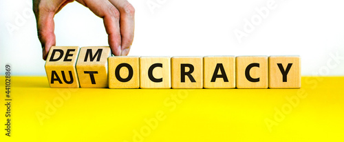 Democracy or autocracy symbol. Businessman turns wooden cubes and changes the word autocracy to democracy. Beautiful white background, copy space. Business and democracy or autocracy concept. photo