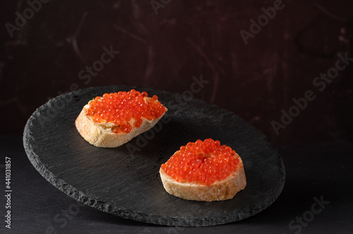 Sandwiches with red caviar on a black tray. Serving caviar sandwiches. Red and black.