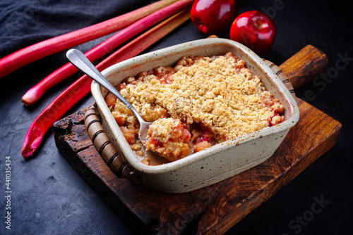 Traditional English crumble cake with rhubarb and apple with backed topping served as close-up in backing form photo