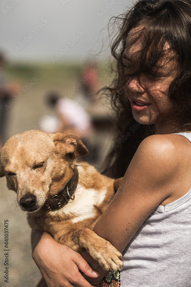 The young womanl holds the red dog in her arms The young womanl holds the red dog in her arms