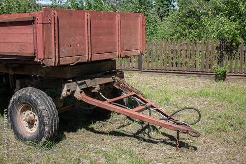 View of a part of the old tractor trailer. Summer rest day in the village. Hitching a cargo trailer. Wooden fence on a sunny day in the summer in the garden.