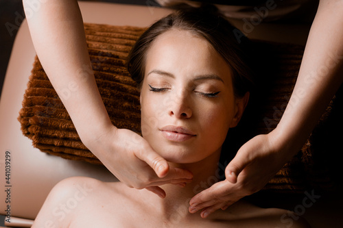 Neck and face massage in the spa. Masseur is making facial beauty treatments for an attractive female model. Relaxation.