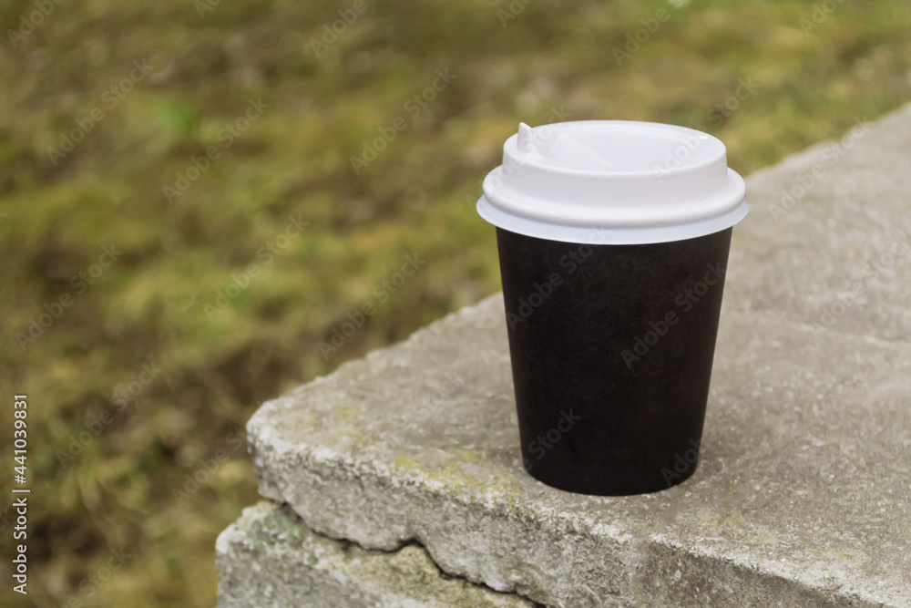 A cardboard cup of coffee sits on a stone curb. Take coffee outside. A cardboard cup of coffee sits on a stone curb. Take coffee outside.