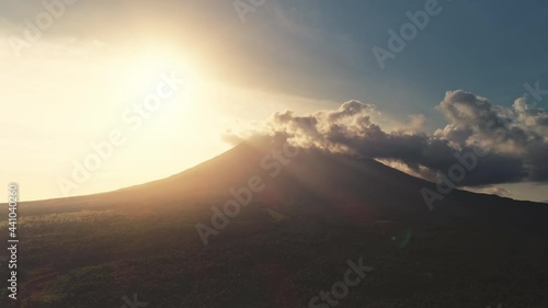 Aerial sunset over volcano erupt. Silhouette of mount. Countryside nobody nature landscape. Sun rays light above tropical green trees, plants and hills. Landmark of Mayon mountain, Philippines, Asia photo