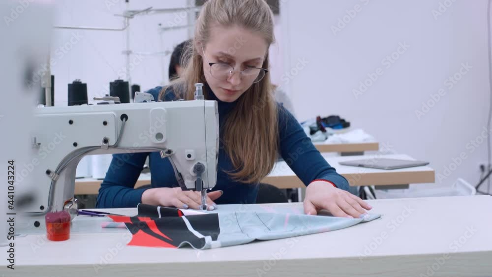 Woman Seamstress Works On Sewing Machine In Clothes Factory. Female ...