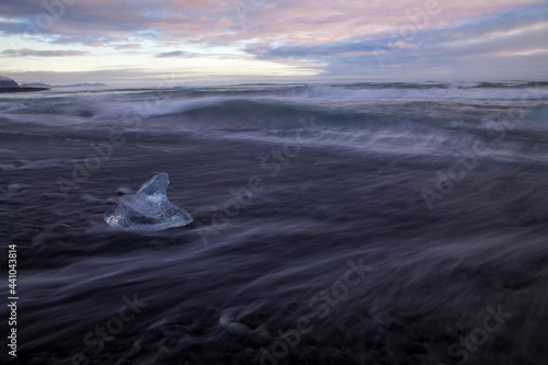 A single chunk of glacial ice lies in the water at a black sand beach near Jokulsarlon Glacier Lagoon in southeastern Iceland 