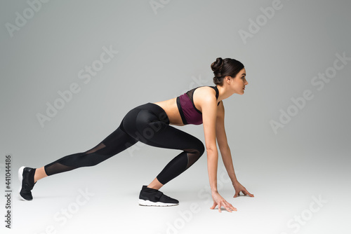 side view of woman wearing black sportswear in low start position on grey background. © LIGHTFIELD STUDIOS