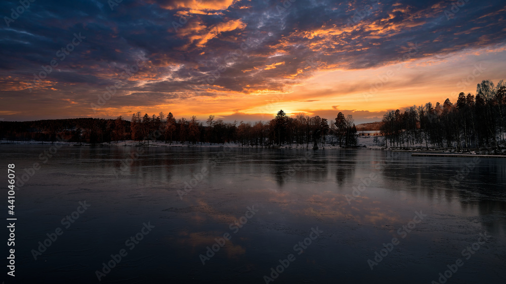 Ice cold reflections. The lake is frozen, the sky is on fire and reflecting in the ice. Shot in Norway, Oslo marka. 