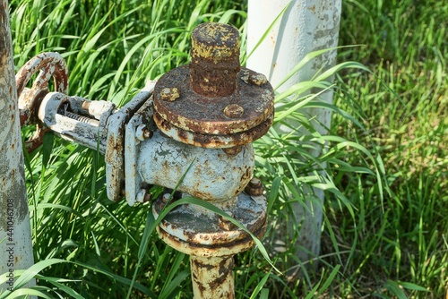 Canvas-taulu one large gray iron valve and a yellow gas pipe overgrown on a green grass in th