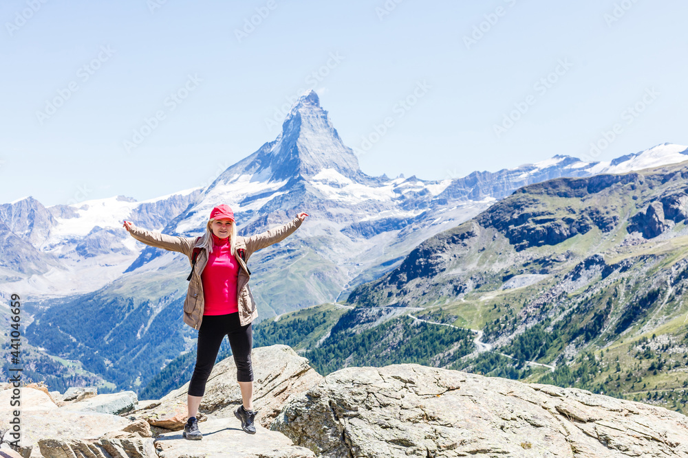 Woman on mountain top of mountain landscape around lake and blue sky.