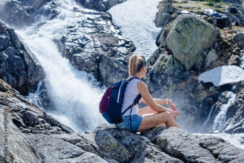 Rear view woman sitting at Siklawa waterfall in the Polish Tatra Mountains.