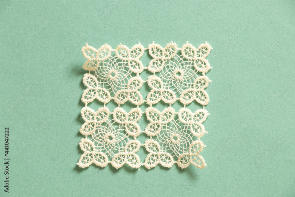 knitted white lace doily lies on a colored paper background - obrazy, fototapety, plakaty 