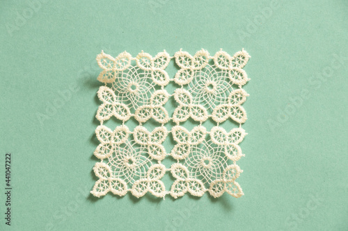 knitted white lace doily lies on a colored paper background