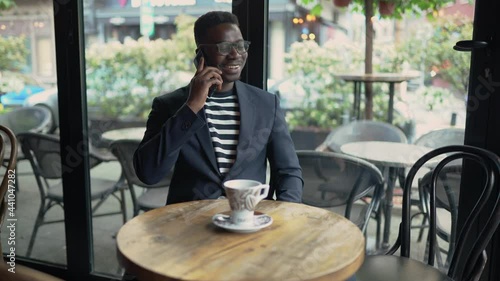 Smiling businessman talking on the phone at a bar.