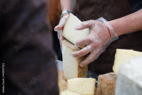 cheese shop in the market. The farmer cuts large chunks of cheese for the buyer.