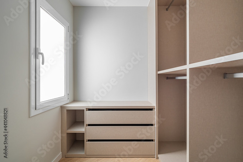 New built-in furniture in a small dressing room. Modern and empty storage room with wardrobe, drawers and plenty of space for hangers. © Pavel