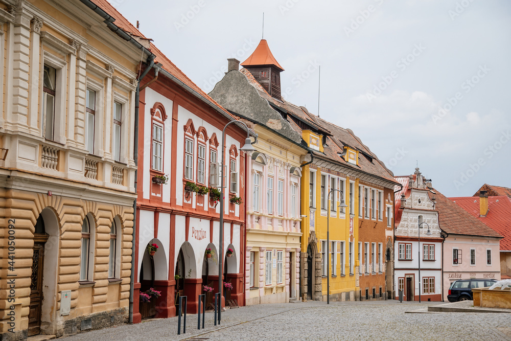 View of the Trckovo square with cobble stone street, colorful houses, a water fountain, tree and green lawn on sunny summer day, historic center, medieval city Opocno, Czech Republic