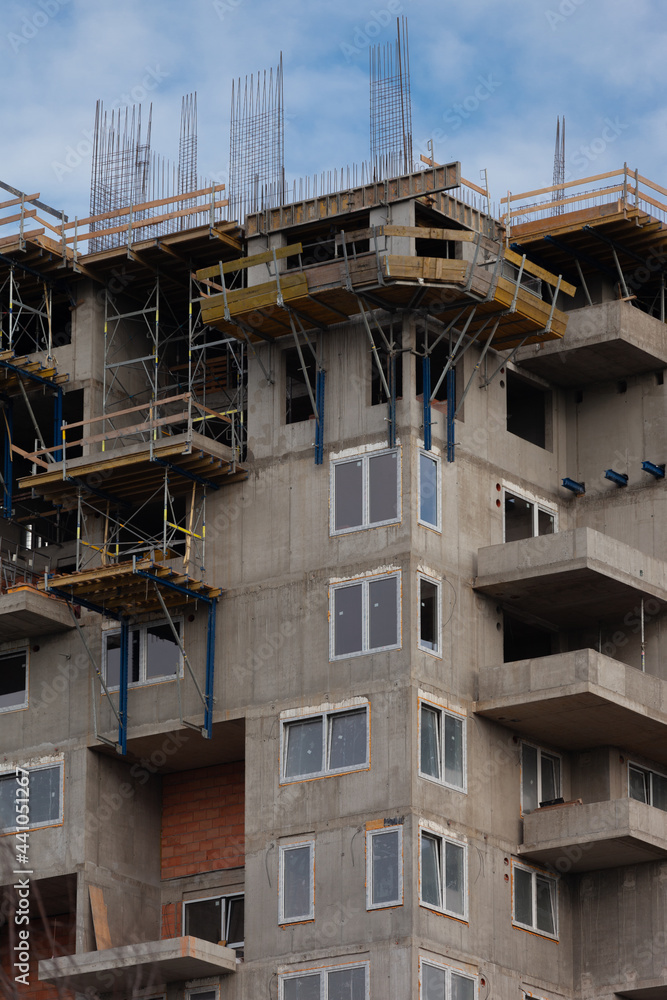 Un immeuble en construction avec des échafaudages fixés sur la façade. Les fenêtres sont posées presque partout. Le béton est visible. Un immeuble en construction avec des échafaudages fixés sur la façade. Les fenêtres sont posées presque partout. Le béton est visible.