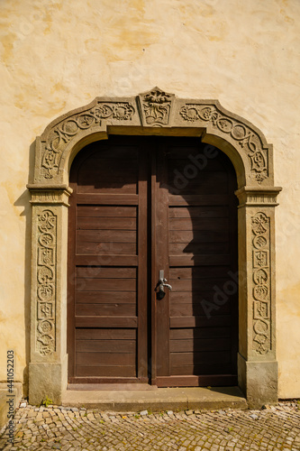 Renaissance Church of the Nativity Virgin Mary, historic center in medieval town, ancient stone portal, old wooden door, summer day, Opocno, Czech Republic