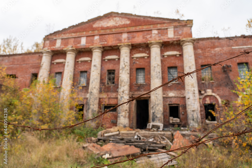 Abandoned brick factory in autumn forest and thorn fence