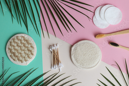 Eco-friendly facial care products. Facial sponges, cotton pads, ear sticks and a pair of toothbrushes on a beige pink and green background. Zero waste and eco concept