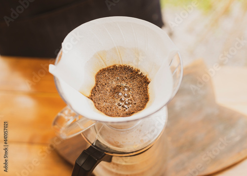 Barista making coffee pouring hot water on paper filter on top of glass coffee jar. Brazilian organic artisanal bakery small business concept.
