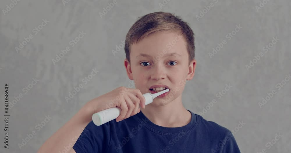 The boy brushing his teeth with an electric brush. Child does oral hygiene The boy brushing his teeth with an electric brush. Child does oral hygiene