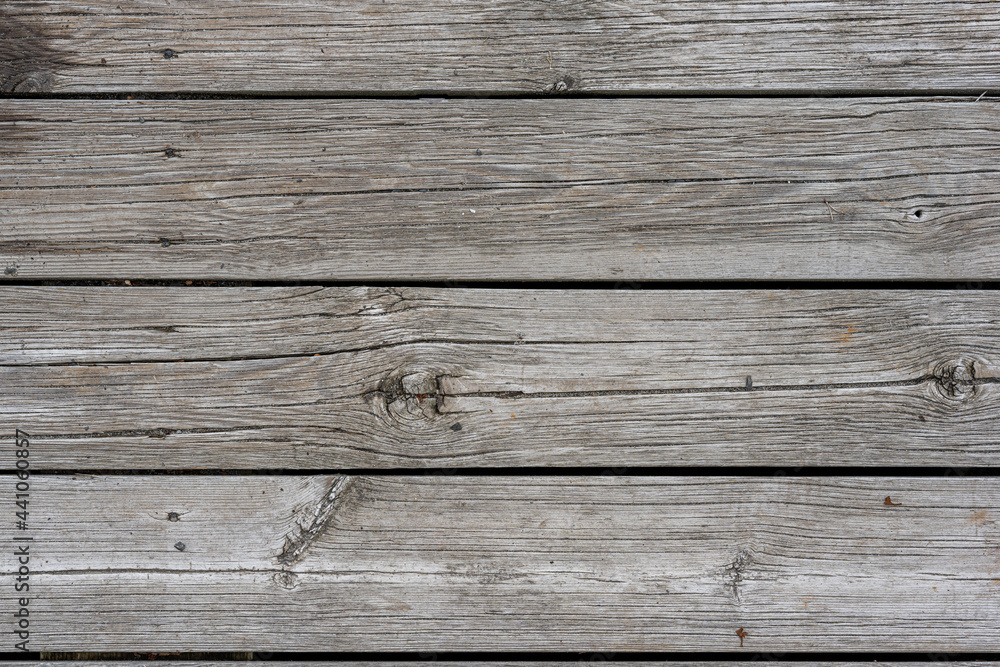 Old and weathered grey floor wall planks with narrow gaps and old nails