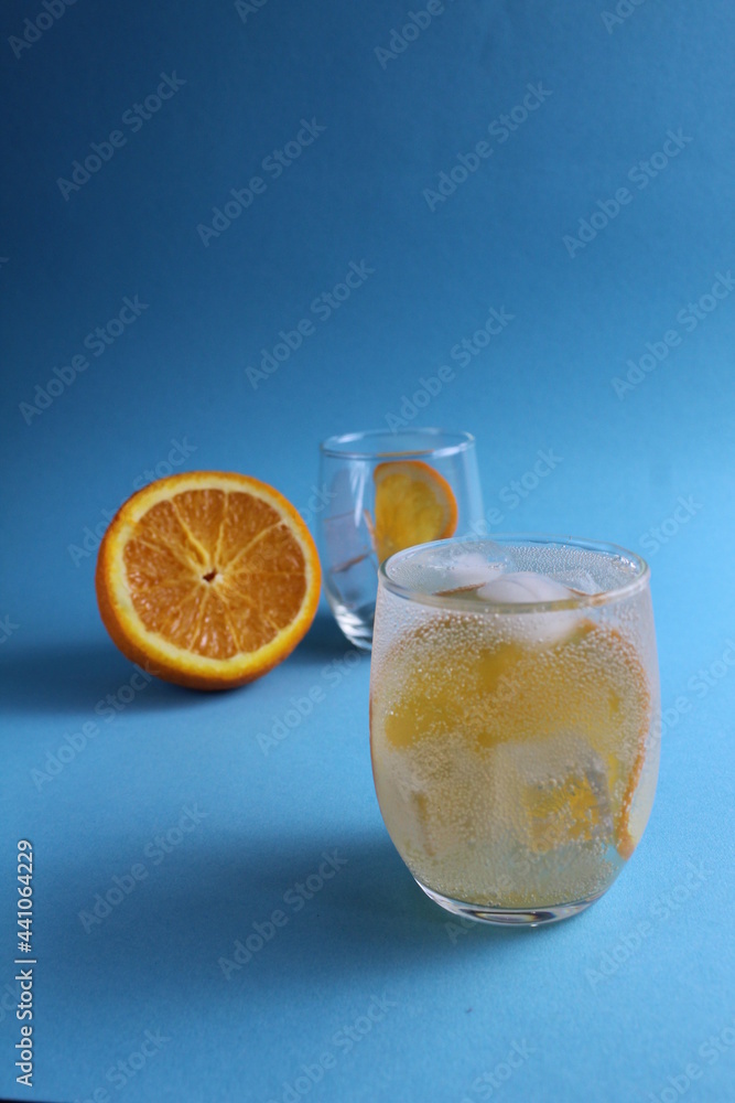 Step-by-step making of lemonade. Step 2. Pour the fruit orange with soda water. A glass of lemonade orange on a blue background with a place for text . close-up Step-by-step making of lemonade. Step 2. Pour the fruit orange with soda water. A glass of lemonade orange on a blue background with a place for text . close-up