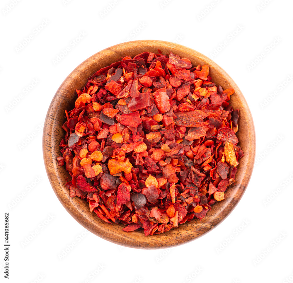 Dried red chili flakes in wooden bowl, isolated on white background. Chopped chilli cayenne pepper. Spices and herbs. Top view. Dried red chili flakes in wooden bowl, isolated on white background. Chopped chilli cayenne pepper. Spices and herbs. Top view.