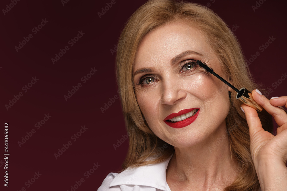 Portrait of a beautiful elderly woman in a white shirt with classic makeup and blond hair. Portrait of a beautiful elderly woman in a white shirt with classic makeup and blond hair.
