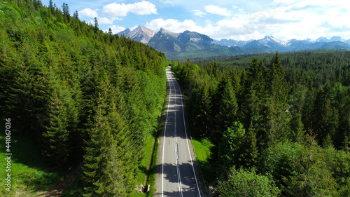 Fototapeta Naklejka Na Ścianę i Meble -  Aerial view of mountain range, road leading to the mountains and rocky brook. Alpine panoramic view.