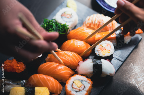 Salmon Sashimi in Japanese buffet restaurant menu.Fresh salmon sushi.Asian friends people using chopsticks eating sashimi sushi set Japan in restaurant.Asian Food Menu.seafood sashimi.People and food photo