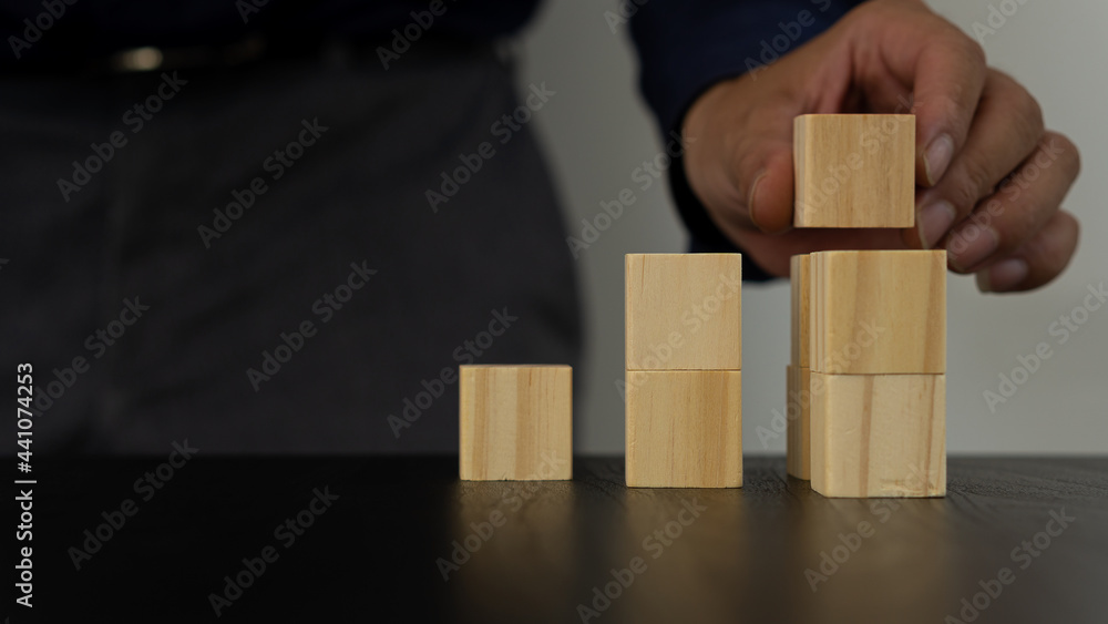 young business man holding wooden cubes. The wooden cubes are arranged in the shape of a pyramid on a white background table and you can put your own message. business idea young business man holding wooden cubes. The wooden cubes are arranged in the shape of a pyramid on a white background table and you can put your own message. business idea