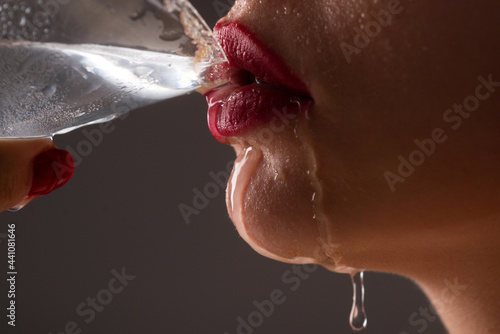 Woman drink water cocktail. Close up wet sexy lips. Young girl drinking red lip cocktail closeup. photo