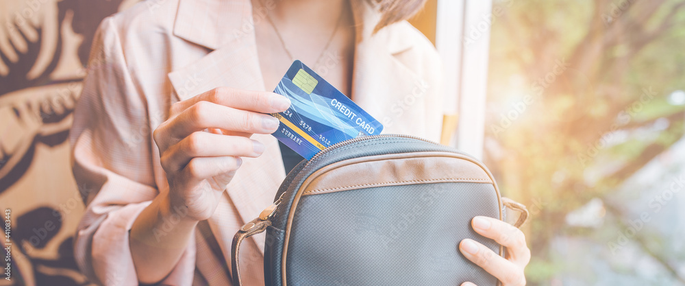 Woman takes a credit card out of her pocket to make a purchase.