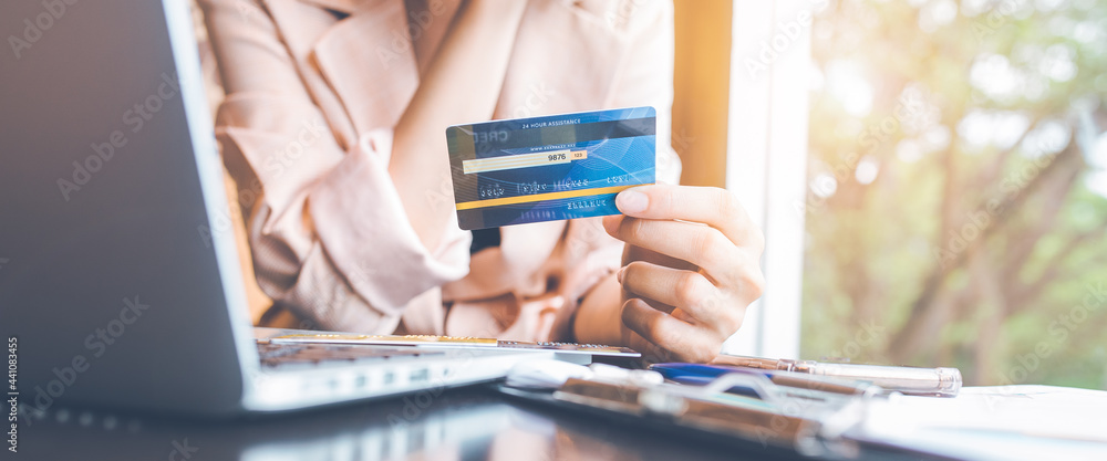 Women hold credit cards to shop online with a laptop computer.