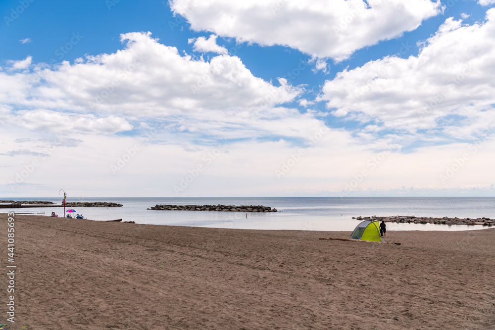 Beach at midday in June with few users and big sky.  Shot in the Toronto Beaches