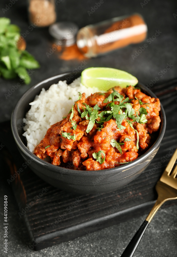 Bowl with tasty chili con carne, rice and lime on dark background, closeup Bowl with tasty chili con carne, rice and lime on dark background, closeup