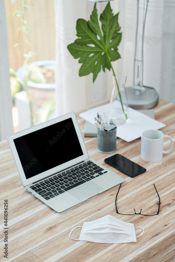 Opened laptop, glasses and medical mask on desk of business person or student Opened laptop, glasses and medical mask on desk of business person or student