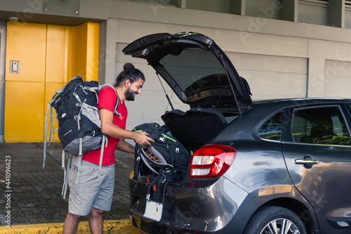 Man carrying a suitcase into the trunk of the car, ready to go on a trip