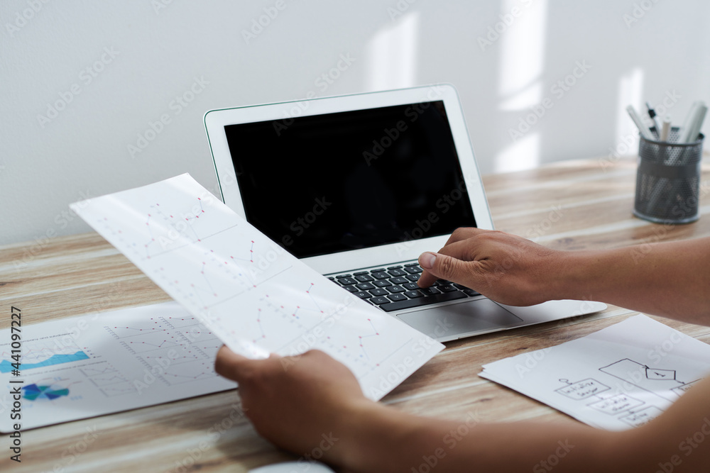 Hands of entrepreneur checking line charts when working on laptop at desk in home office Hands of entrepreneur checking line charts when working on laptop at desk in home office