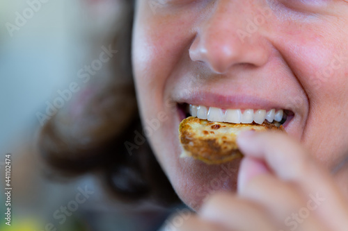 A woman has white teeth eating fries with selective focus