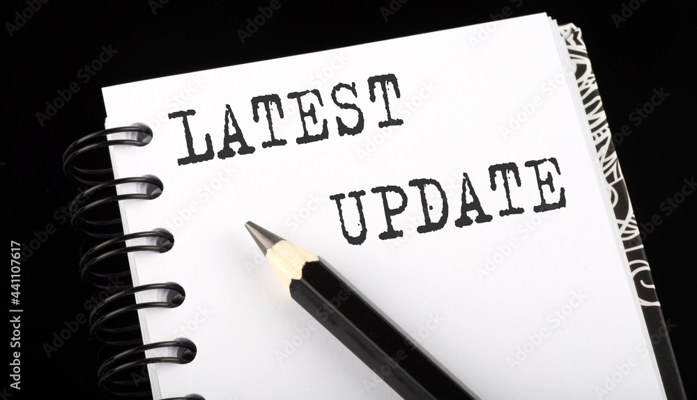 LATEST UPDATE written text in small notebook on a black background LATEST UPDATE written text in small notebook on a black background
